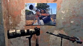 Lübnan'da İsrail tankından açılan ateşle 13 Ekim'de öldürülen Reuters kameramanı İssam Abdullah'ın posteri, kana bulanan fotoğraf makines, ve tripodu