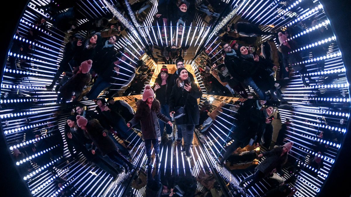 People stand in a giant kaleidoscope, an installation by French artist Guillaume Marmin, during the Festival of Lights (Fete des Lumieres).