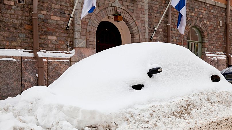 Ein verschneites Auto in Helsinki.