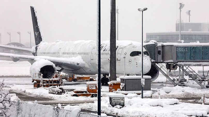 A Lufthansa aircraft is parked at the snow-covered Munich airport, Germany, 2 December 2023.