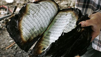 A Palestinian holds a copy of the Quran as he inspects damage to a mosque in Gaza City, Wednesday, April 16, 2008