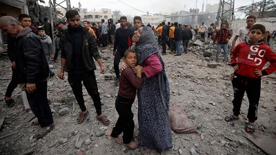 امرأة فلسطينية وابنتها تقفان بين الركام بعد قصف إسرائيلي على خان يونس