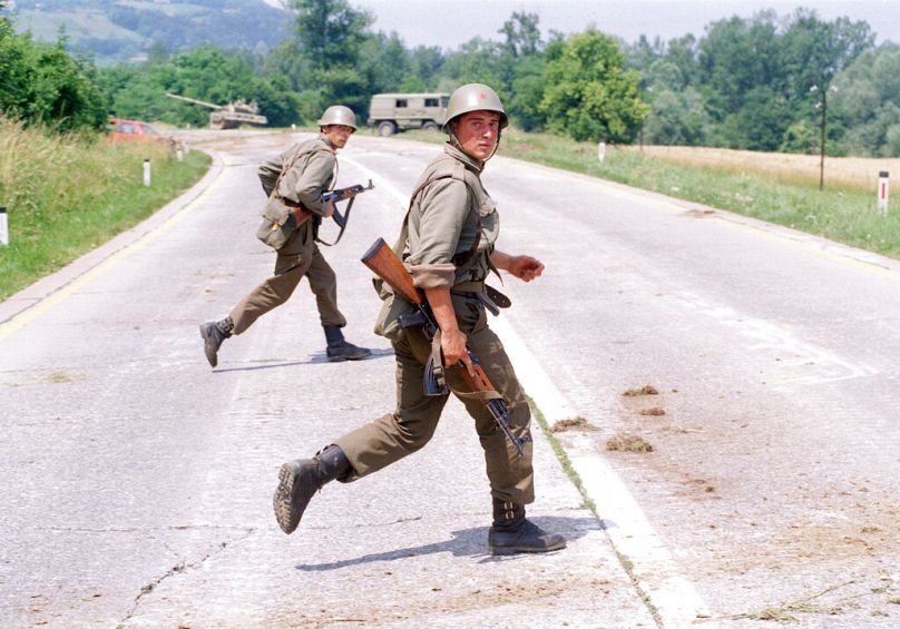 Two Yugoslav soldiers take cover during firefights with members of the Slovene defense forces near Brezice, 15 miles from Zagreb, July 1991