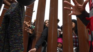 مهاجرون يصلون عبر الجدار الحدودي للحصول على الملابس التي يوزعها المتطوعون في سان دييغو