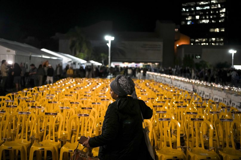 A woman walks by empty chairs tied together in an art installation depicting hostages held by Hamas in the Hostages Square at the Museum of Art in Tel Aviv, November 2023