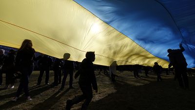 Archive : des enfants jouent sous un drapeau ukrainien géant pour protester contre l'intervention russe en Ukraine en 2014, en Lituanie.