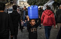 A child is seen as Palestinians meet their water needs from mobile tanks after great damage to the city's infrastructure due to Israeli attacks in Khan Yunis, Gaza 