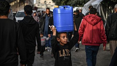 A child is seen as Palestinians meet their water needs from mobile tanks after great damage to the city's infrastructure due to Israeli attacks in Khan Yunis, Gaza 