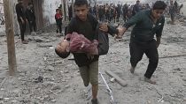 طفل فلسطيني يحمل طفلا فلسطينيا أصيب جراء القصف الإسرائيلي على خانيونس