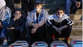 متظاهرون يجلسون أمام توابيت وأكفان رمزية للأطفال خلال مسيرة لدعم غزة أمام مبنى المتحف الوطني في بيروت في 8 ديسمبر 2023،