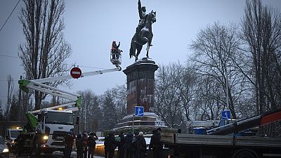 Un grupo de personas observan cómo se desmantela la estatua de Shchors en Ucrania.