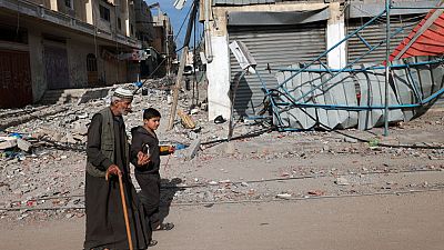 A young boy holds the hand of an old man as they walk along a street in Rafah in the southern Gaza Strip