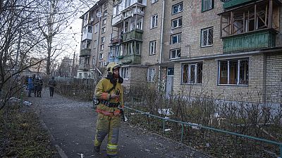 Un vigile del fuoco esamina i danni a un edificio dopo un attacco di droni russi a Kiev, sabato 25 novembre 2023.