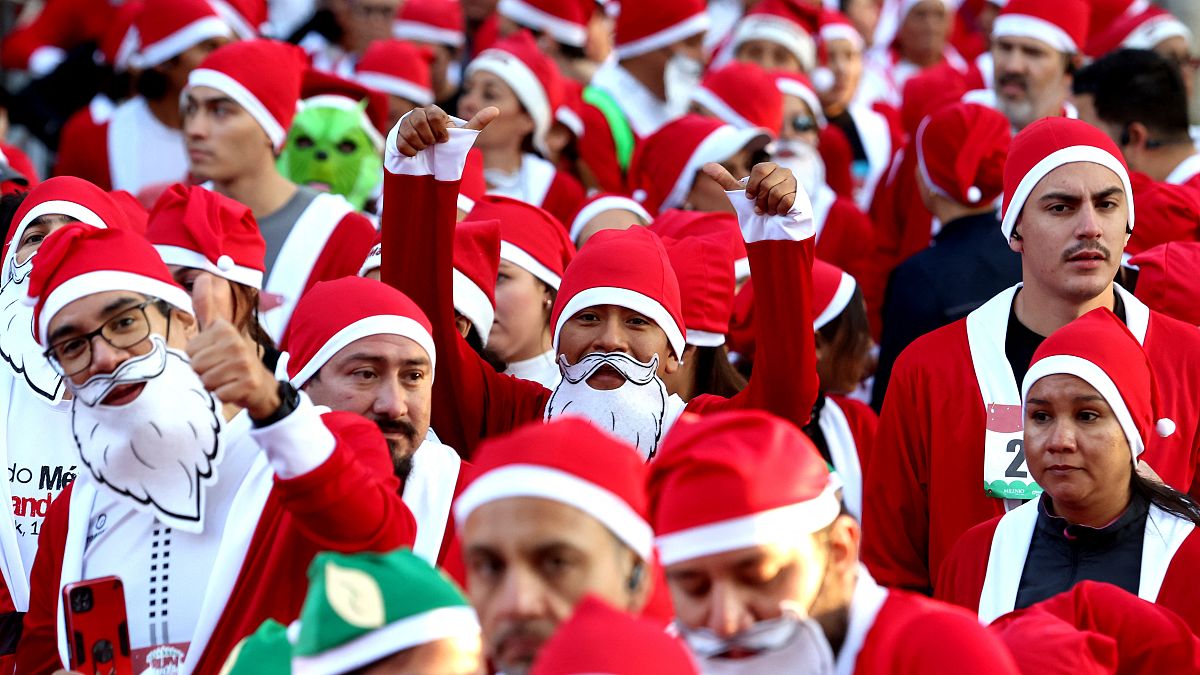 Imagen de varias personas ataviadas con los trajes de Papá Noel y de elfo, en el transcurso de la carrera Run Santa Run.