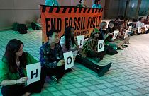 Demonstrators hold signs that reads "hold the line" and "end fossil fuels" during COP28. 