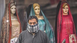 Imagen de un hombre que espera al autobús, frente a una tienda de ropa, la localidad de Srinagar, Cachemira.