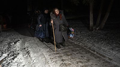 Mujeres cargan su equipaje después de tomar un viaje en autobús después de cruzar la frontera con Rusia en la región de Sumy en Ucrania, el miércoles 22 de noviembre de 2023.