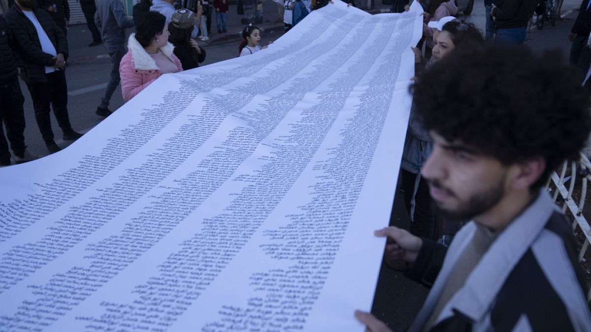 Tüntetők az Izrael-Hamász háború palesztin áldozatainak neveit tartalmazó lepedővel a ciszjordániai Ramallahban