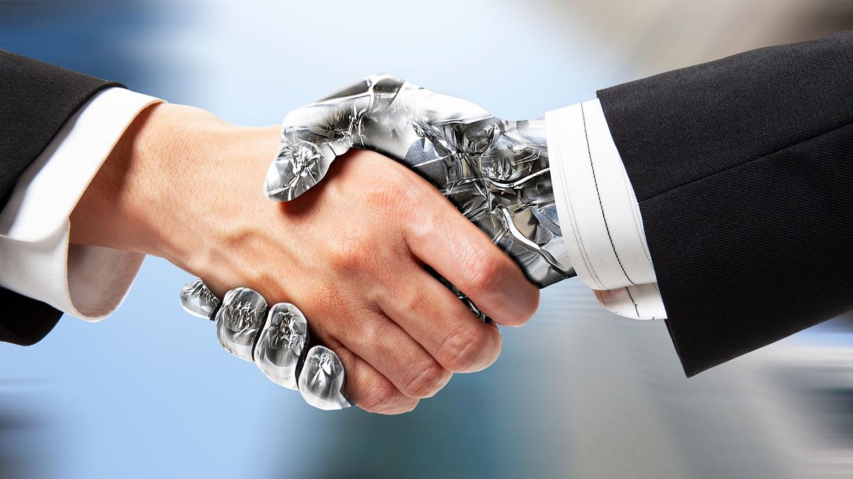 Un humain et un robot se serrent la main.