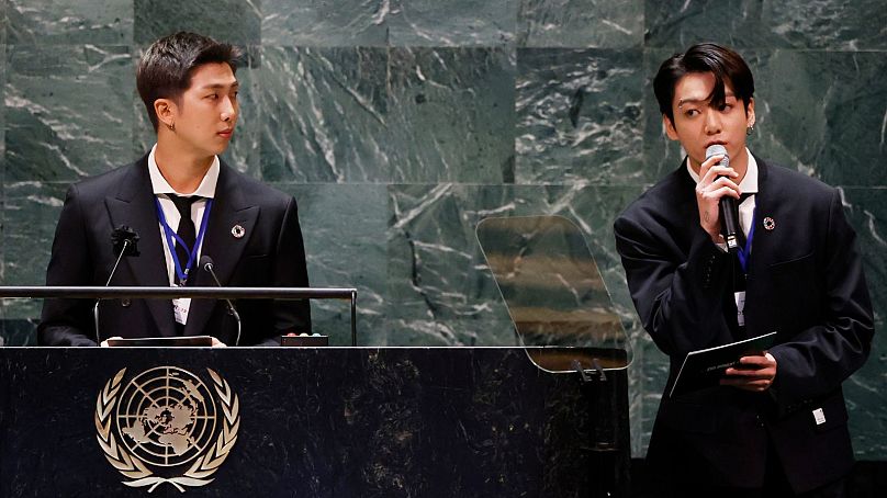 آر.ام. (چپ) وجونگ کوک (راست) در حال سخنرانی در سالن مجمع عمومی سازمان ملل به تاریخ ۲۰ سپتامبر ۲۰۲۱