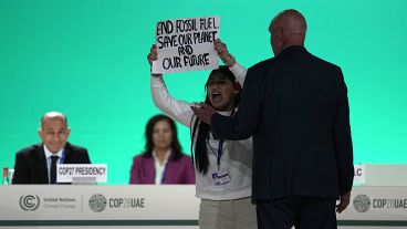 ناشطة ترفع لافتة ضد استخدام الوقود الأحفوري في مؤتمر قمة المناخ في دبي