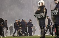 Policemen detain a fan of Panathinaikos during clashes at the pitch of Apostolos Nikolaides stadium  in Athens, Saturday, Nov. 21, 2015.