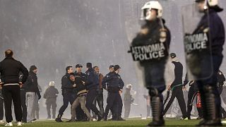 Policemen detain a fan of Panathinaikos during clashes at the pitch of Apostolos Nikolaides stadium  in Athens, Saturday, Nov. 21, 2015.