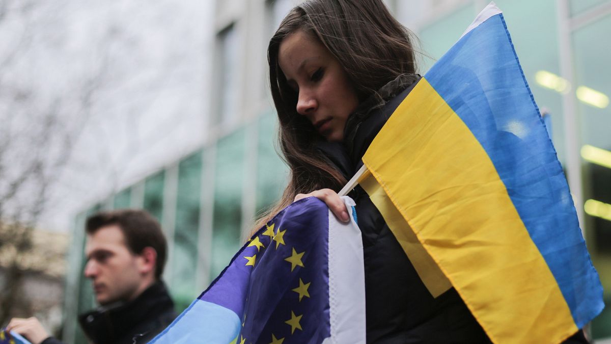Un manifestant avec un drapeau ukrainien et un drapeau de l'UE