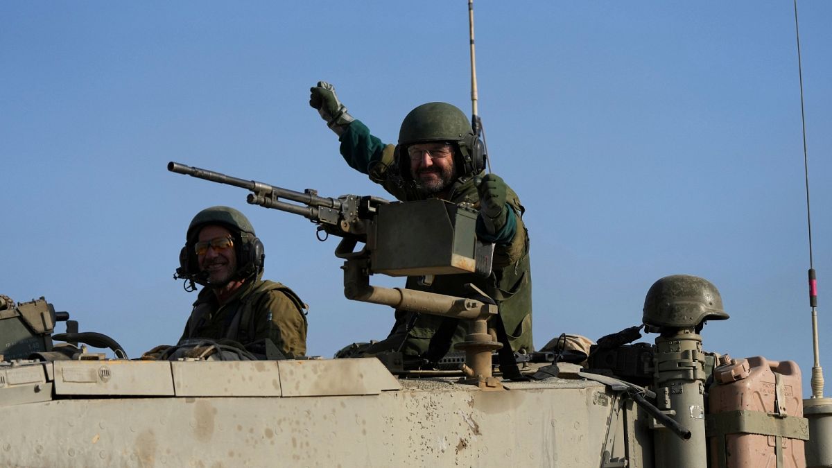 Israeli soldiers wave from a tank near the border between Gaza and southern Israel on Tuesday, Dec. 12, 2023.