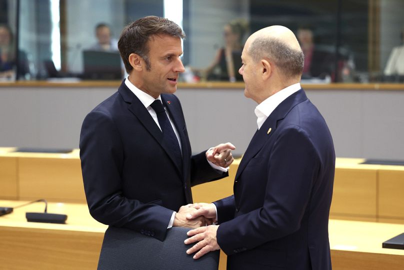 France's President Emmanuel Macron speaks with Germany's Chancellor Olaf Scholz during a round table meeting at the European Council building in Brussels, June 2023