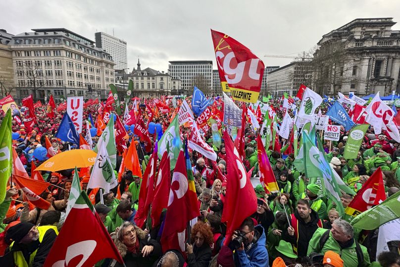 Protestors hold flags and gather during a demonstration against austerity measures in Brussels, 12 December 2023