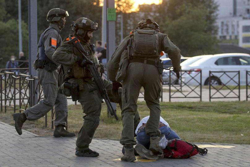 Police officers kick a demonstrator during a mass protest following presidential election in Minsk, August 2020