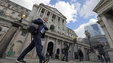 A man walks past the Bank of England in the financial district in London