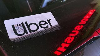 Ein Uber-Logo hinter der Windschutzscheibe eines Autos vor einer Sushi-Bar