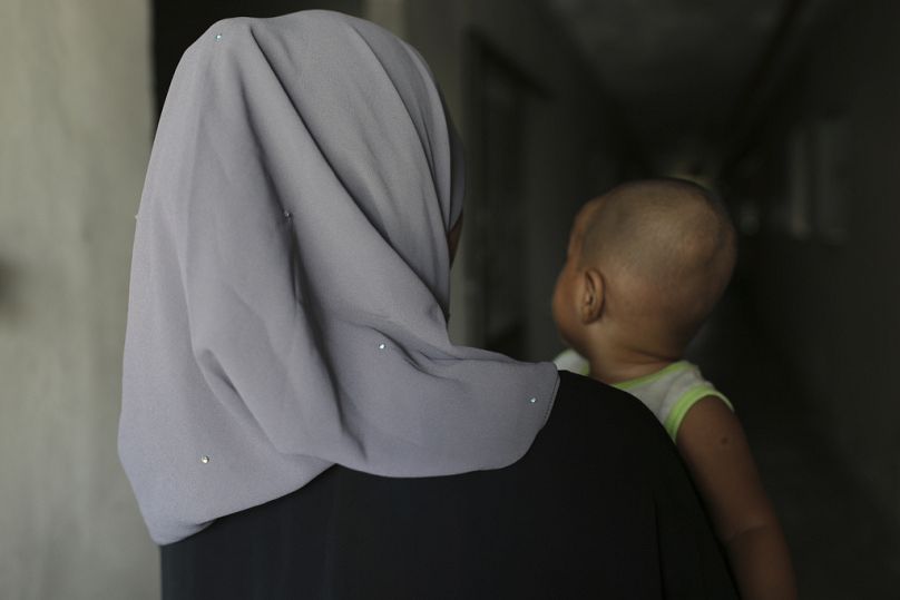 Malezya'da 16 yaşındaki Rohingya çocuk gelin "T", kendisinden yaşça büyük bir adamla evlenmek zorunda kalmış. Bebeğini kucağında tutuyor. Kocası evden çıkmasına izin vermiyor