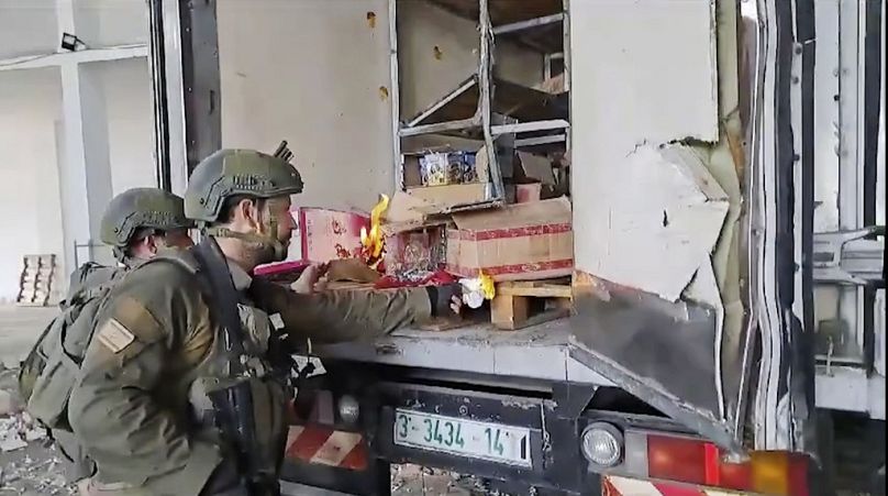 This image made from an undated video shared on X shows Israel Army troops trying to burn food and water supplies in the back of an abandoned truck in Gaza
