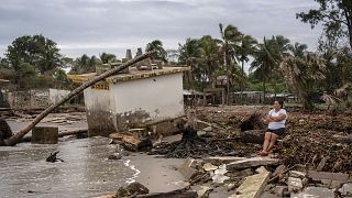 Guadalupe Cobos sits along the shore amid debris caused by flooding driven by a Gulf of Mexico sea-level rise, in her coastal community of El Bosque, in the state of Tabasco,