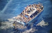 scores of people sit on a battered fishing boat that later capsized and sank off southern Greece.