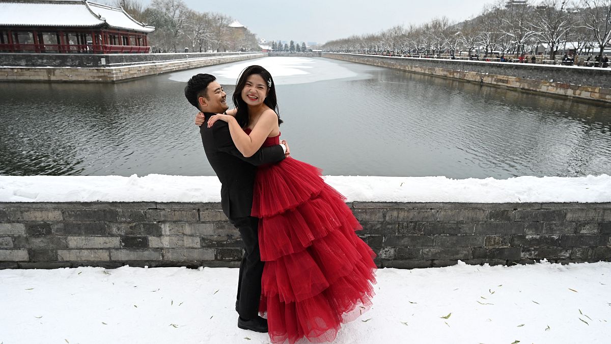 زوجان يلتقطان صور زفافهما في الثلج بجانب الخندق الذي يحيط بالمدينة المحرمة