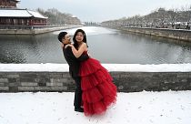 زوجان يلتقطان صور زفافهما في الثلج بجانب الخندق الذي يحيط بالمدينة المحرمة