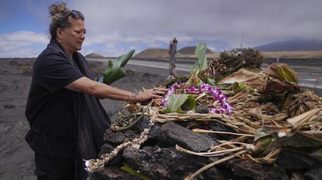 Kealoha Pisciotta, a cultural practitioner and longtime activist, lays offerings before praying at an "ahu," or ceremonial platform, part of the way up Mauna Kea 