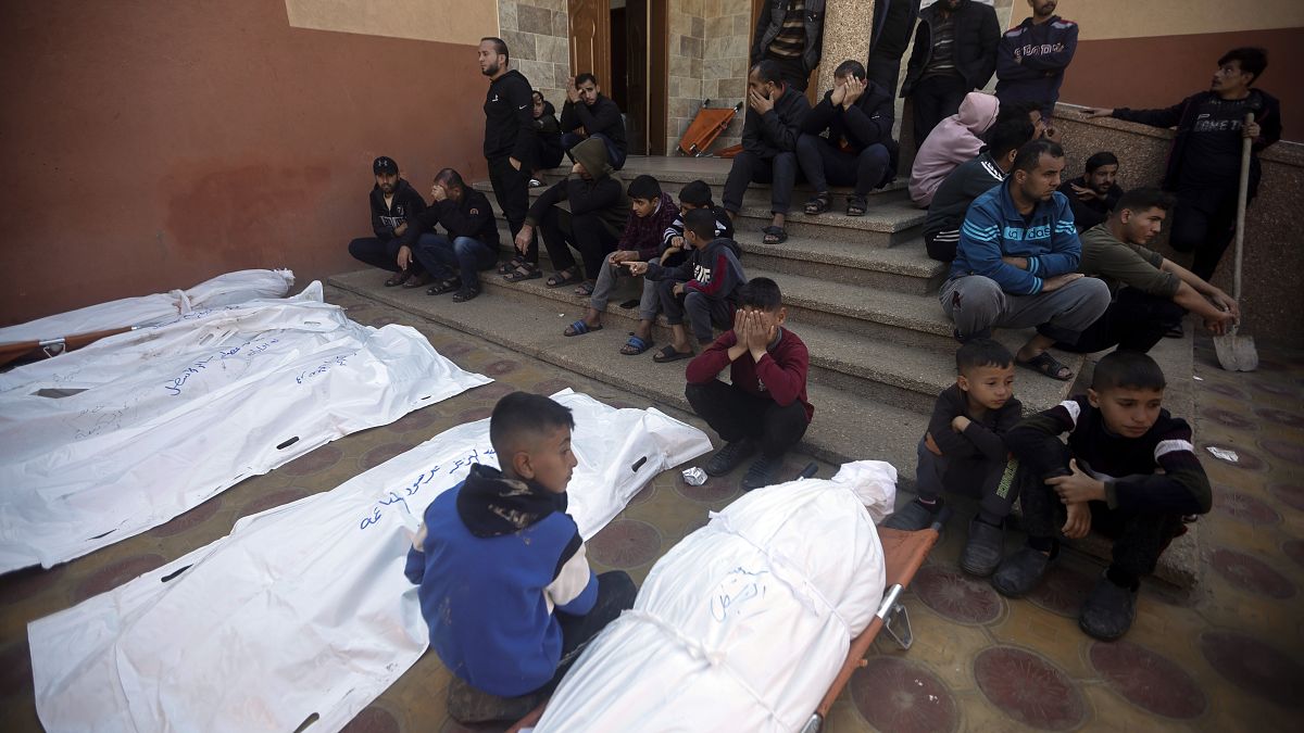 أطفال فلسطينيون يجلسون قرب جثث تعود لأفراد من عائلاتهم قتلوا في القصف الإسرائيلي على خانيونس