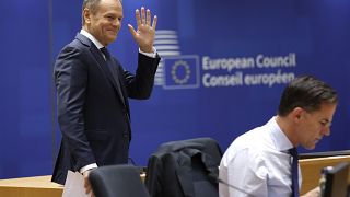 Poland's Prime Minister Donald Tusk, left, waves as he arrives for a round table meeting at an EU summit in Brussels, Friday, Dec. 15, 2023.