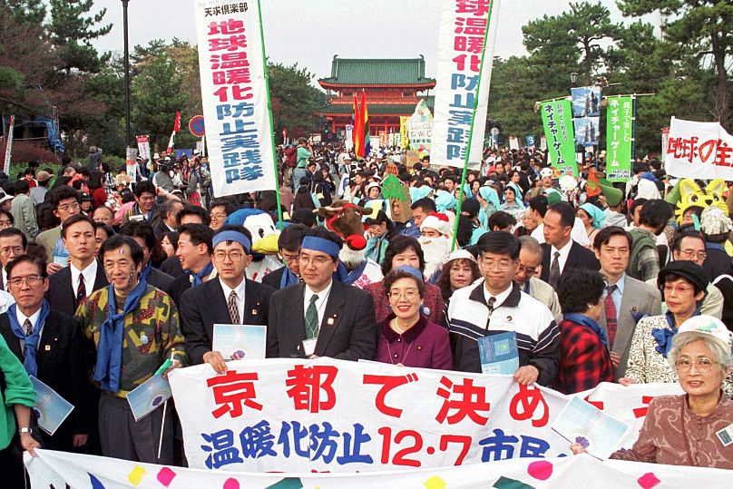 Environmentalists and citizens hold banners calling for reduction of green house gas emissions in front of the Heian shrine in Kyoto, western Japan in 1997