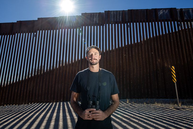 Laiken Jordahl, Southwest conservation advocate, poses next to the US-Mexico border wall in Sasabe, Arizona.