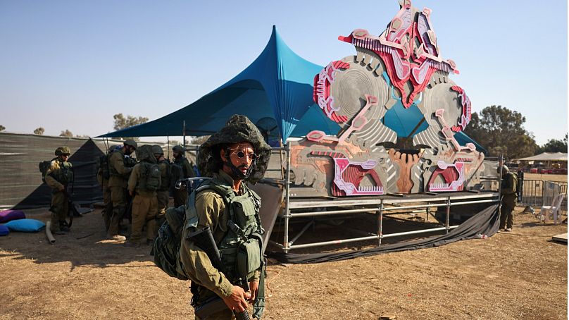 جنود إسرائيليون يقومون بتفتيش موقع الهجوم الذي شنه مسلحون فلسطينيون على مهرجان موسيقى صحراء سوبر نوفا، بالقرب من كيبوتس ريم في صحراء النقب في جنوب إسرائيل في 12 أكتوبر، 2023.