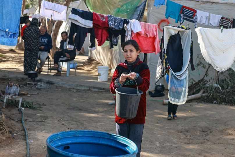 A girl carries a bucket of water at a camp for displaced Palestinians in Rafah in the southern Gaza Strip on Saturday