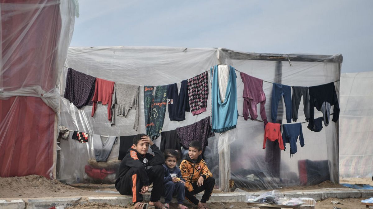 Palestinian children sit in front of tents, set up near seashore, as people try to continue their daily lives under Israeli attacks in Rafah, Gaza