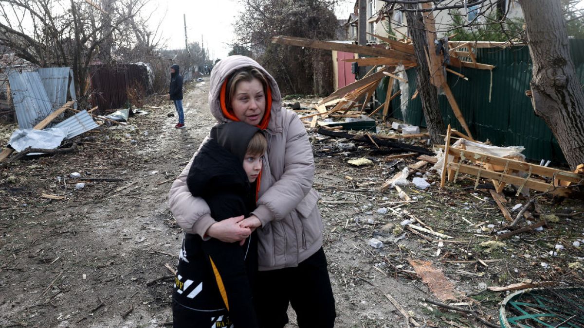 Local residents stand among debris on the street outside a house destroyed as a result of a drone attack in Tairove, Odesa region on Sunday