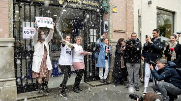 Vendedores de lotería del "Gato Negro" celebran tras vender un billete ganador del primer premio de la lotería de Navidad de España "El Gordo" en 2022